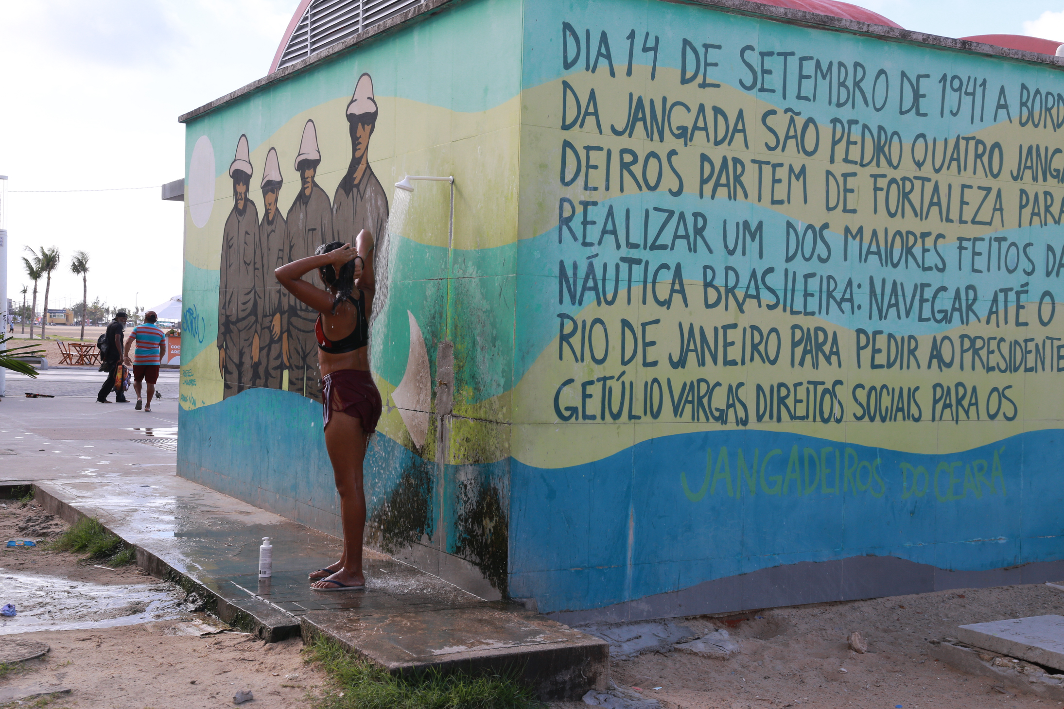 mulher tomando banho num chuveiro externo do banheiro público da beira-mar